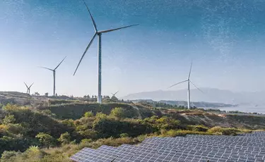 Landscape featuring wind turbines and solar panels under a clear blue sky, representing the brand’s commitment to using renewable energy for manufacturing.