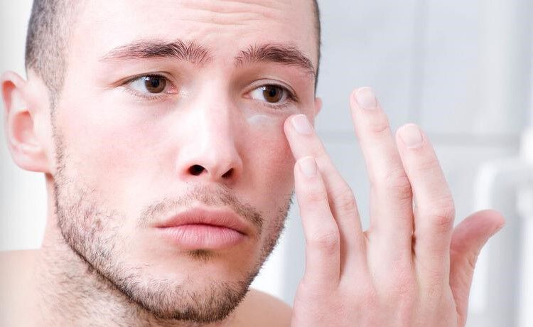 Man applying Kiehl's eye cream under his eye