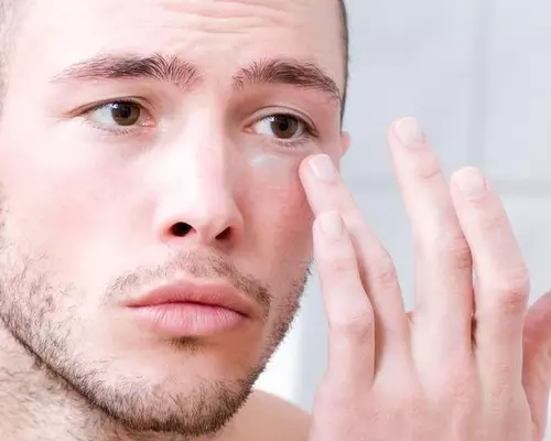 Man applying Kiehl's eye cream under his eye
