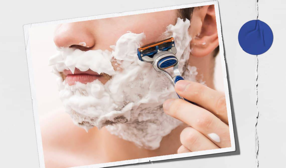 Model with shaving cream on their face shaving their cheek