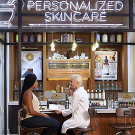 licensed esthetician and customer in Kiehl's store testing discussing skincare treatments.