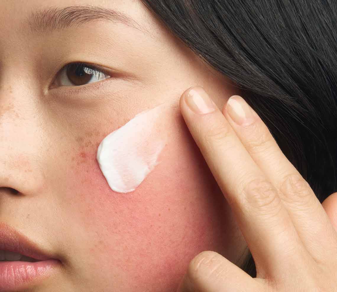 Action shot of the Kiehl's Ultra Facial Barrier-Hydrating Cleanser in use. The image shows the cream-to-foam formula creating a rich lather as it is massaged into the skin, demonstrating a gentle and refreshing cleansing experience.