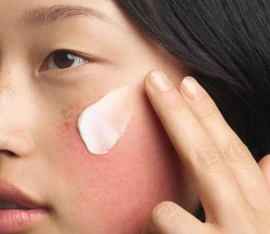 Action shot of the Kiehl's Ultra Facial Barrier-Hydrating Cleanser in use. The image shows the cream-to-foam formula creating a rich lather as it is massaged into the skin, demonstrating a gentle and refreshing cleansing experience.