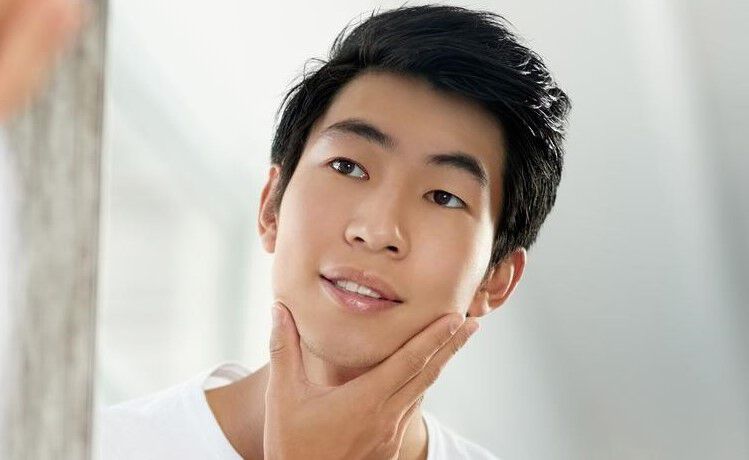 Man looking into mirror with hand on his face