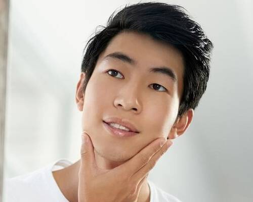 Man looking into mirror with hand on his face
