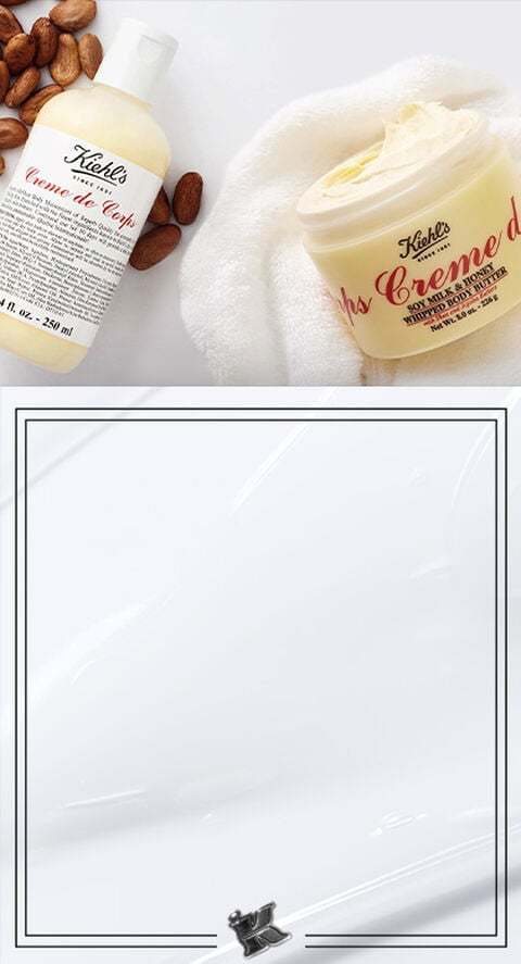 A product shot of Kiehl's Creme de Corps line next to fresh cocoa beans