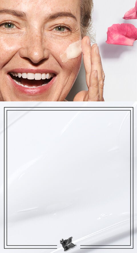 Woman over 50 smiling while putting a cream under her eye.