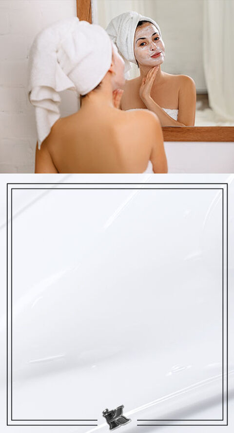 A person in a bathroom mirror smiling in a face mask.