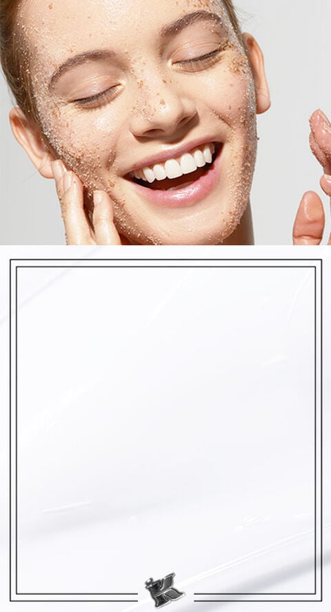 A woman smiling with a face scrub on her face.
