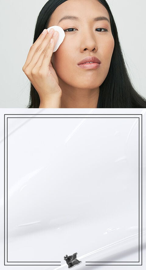 A woman using a cotton pad to remove makeup from her face.