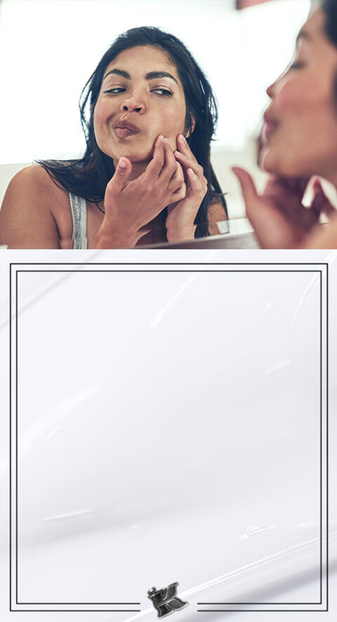 A woman checking her face in the mirror for blemishes.