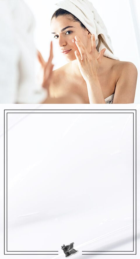 A woman rubbing a lotion into her face.