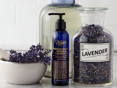 An image of Kiehl's Midnight Recovery Botanical Cleansing Oil next to a canister of fresh lavender.
